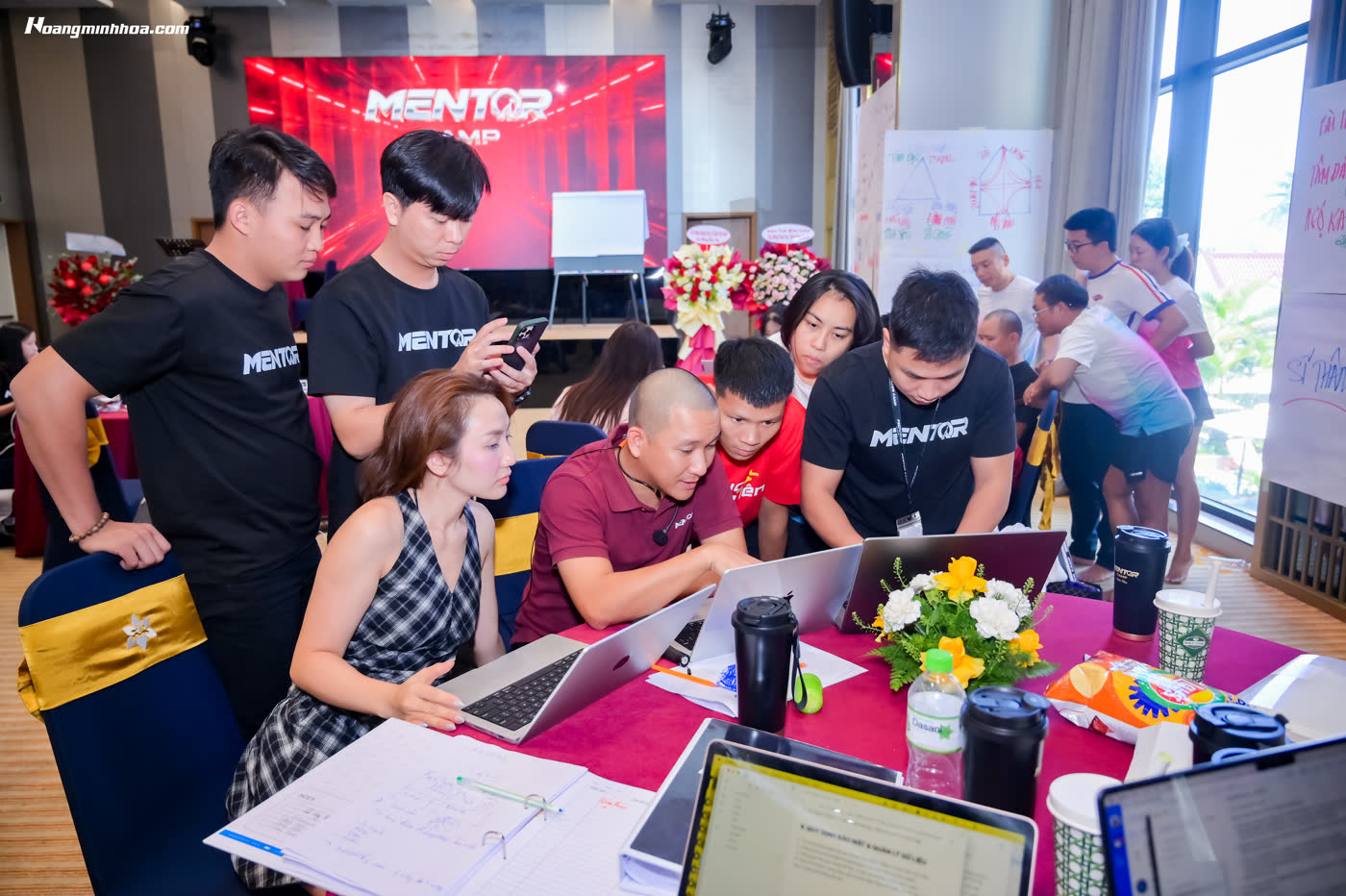 Học viên vây quanh laptop được hướng dẫn trực tiếp tại Mentor Camp